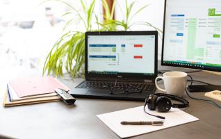 Ein aufgeräumter Arbeitsplatz zu Hause mit Laptop, Monitor und Unterlagen, an dem Weiterbildungskosten für die Steuererklärung zusammengestellt werden