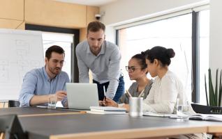 Mitarbeitende arbeiten gemeinsam am Laptop während einer Schulung im Büro