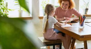 Pädagogin und Kind beim Malen am Tisch, Weiterbildung Grundlagen der Kindheitspädagogik