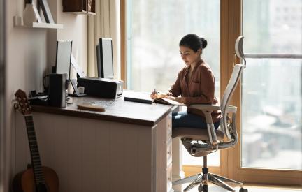 Eine berufstätige Person macht sich am Schreibtisch schriftliche Notizen zum angestrebten Beruf und zur geplanten Weiterbildung