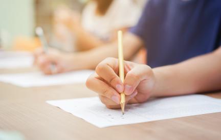Hand schreibt mit Bleistift eine Prüfungsleistung, die Voraussetzung für ECTS Punkte im Fernkurs